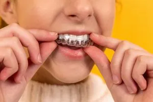 Girl putting invisalign tray in her mouth