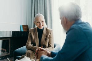 two mature adults sitting across from each other smiling